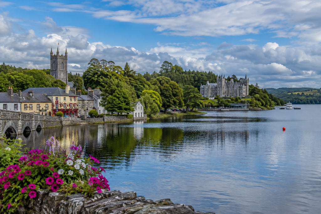 Scenic view of Cong and Lough Corrib in County Mayo, Ireland, with historic stone buildings, lush countryside and calm lake views.