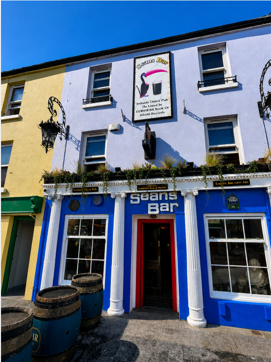 Exterior of Sean’s Bar in Athlone, Ireland, featuring its distinctive blue-and-white façade, traditional entrance and barrels outside Ireland’s oldest pub.