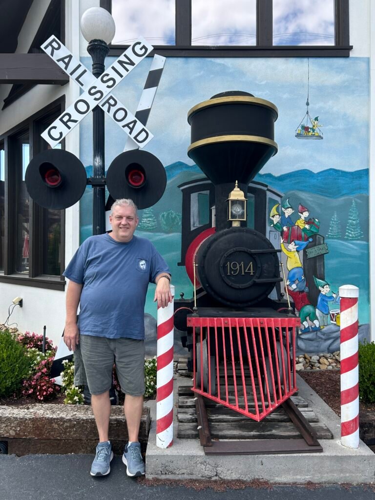 Visitor standing beside the large train display outside The Incredible Christmas Place in Pigeon Forge