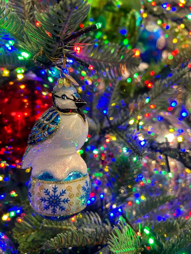 Close-up of a decorative bird ornament on a brightly lit Christmas tree at The Incredible Christmas Place