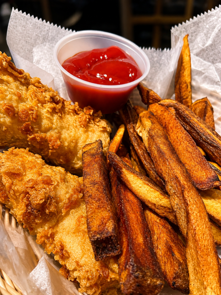 Traditional fish and chips at Dugan's Pub in Wichita, Kansas, featuring hand-battered fish, crispy fries, tartar sauce, and lemon wedges.