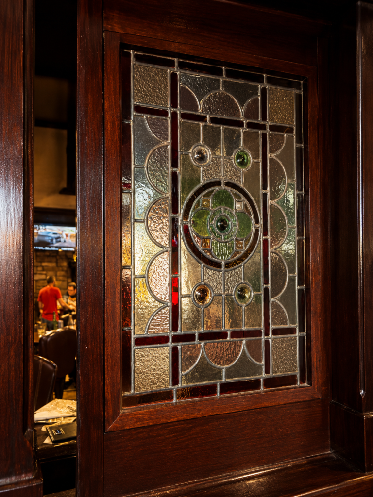 Decorative stained-glass partition inside Dugan's Pub in Wichita, Kansas, featuring textured glass, leaded details, and rich wood trim.