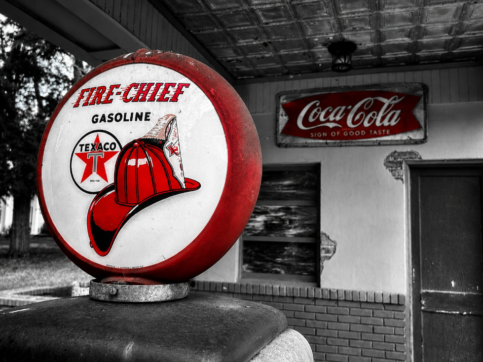 Selective-color image of a red Texaco Fire-Chief gas pump display with a vintage Coca-Cola sign at a Watkinsville service station.
