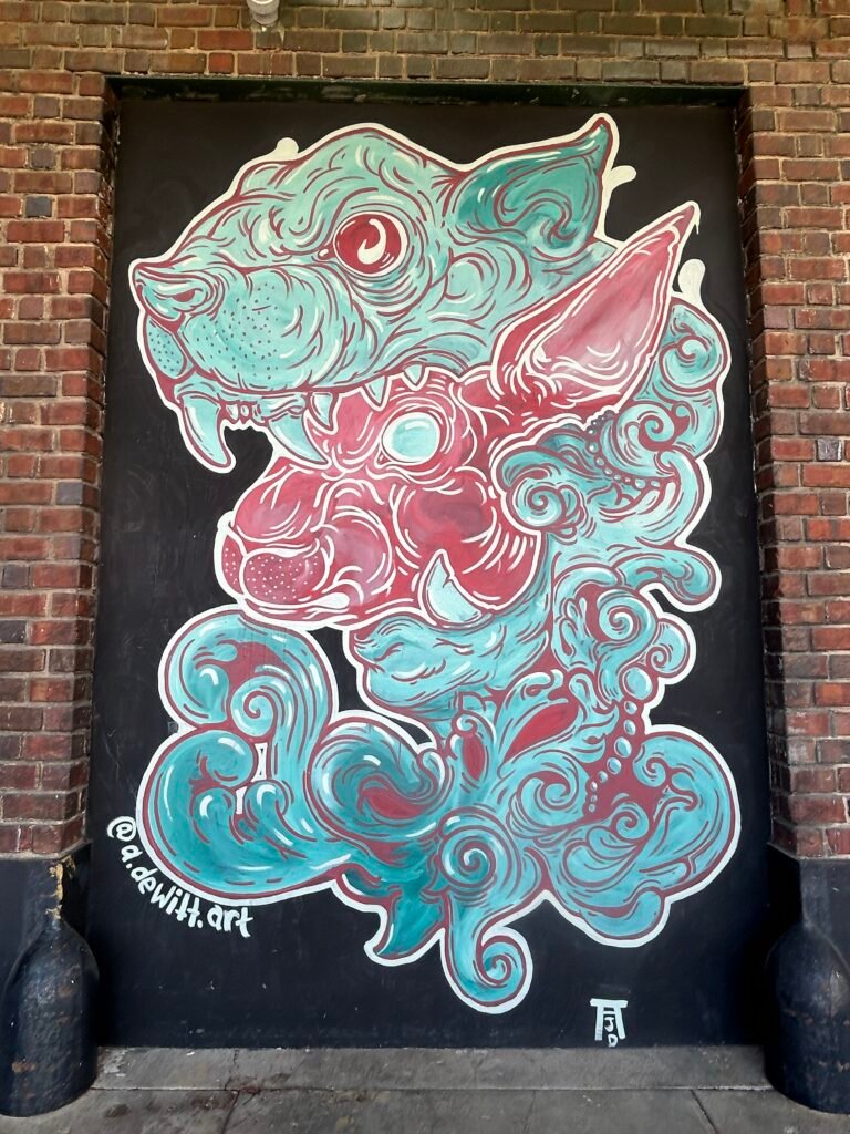 Turquoise and red fantasy creatures surrounded by curling wave and cloud patterns on a black background.