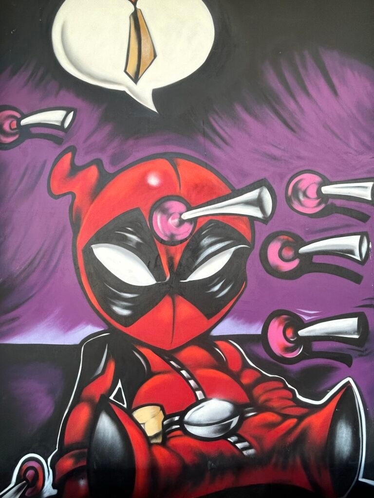Cartoon-style Deadpool mural with arrows, hearts and a purple-and-black background.