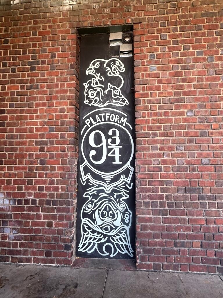 Black-and-white Platform 9¾ mural with stylized animal faces painted on a narrow doorway at the historic train station