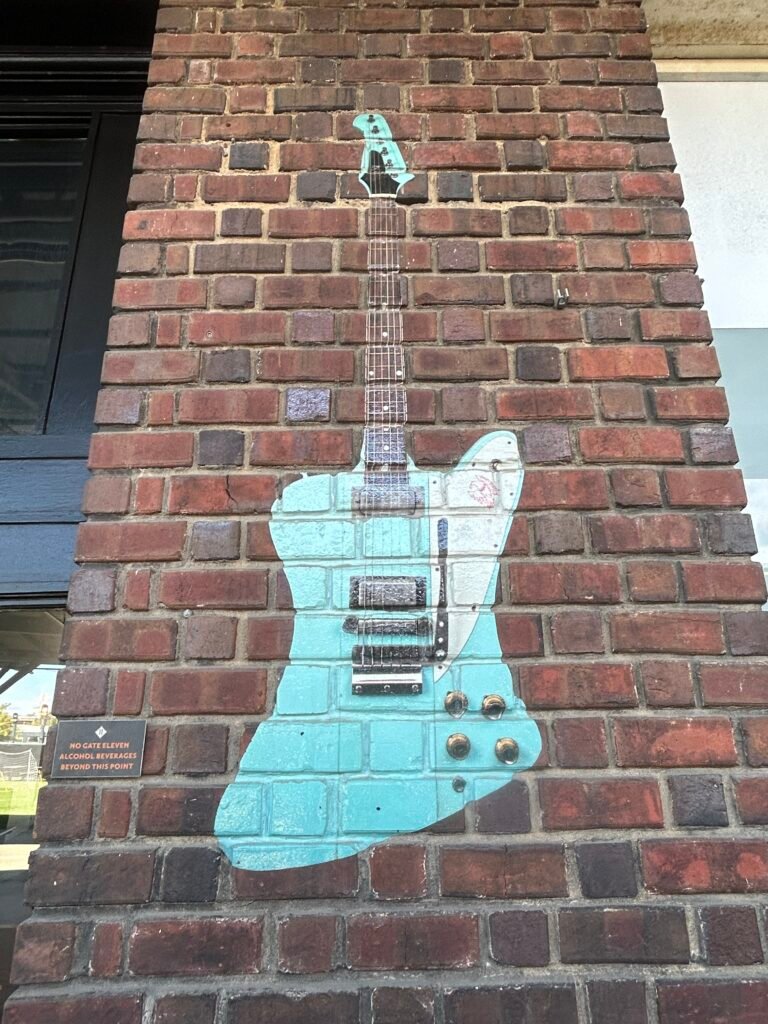 Turquoise electric guitar painted across a red brick wall at the Chattanooga Choo Choo.