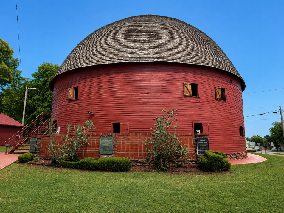 Red circular exterior and shingled domed roof of the historic Arcadia Round Barn in Oklahoma.