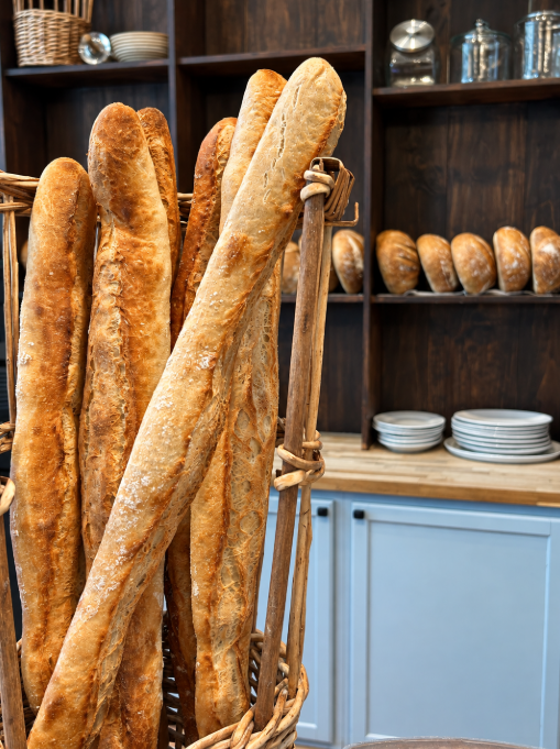 Freshly baked artisan baguettes displayed in a woven basket at The Patisserie on Main