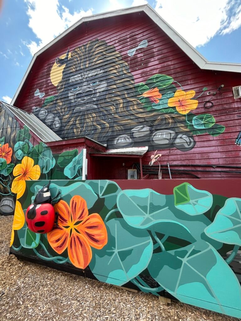 Bigfoot mural surrounded by oversized green leaves and orange flowers at Country Barn in Pigeon Forge.