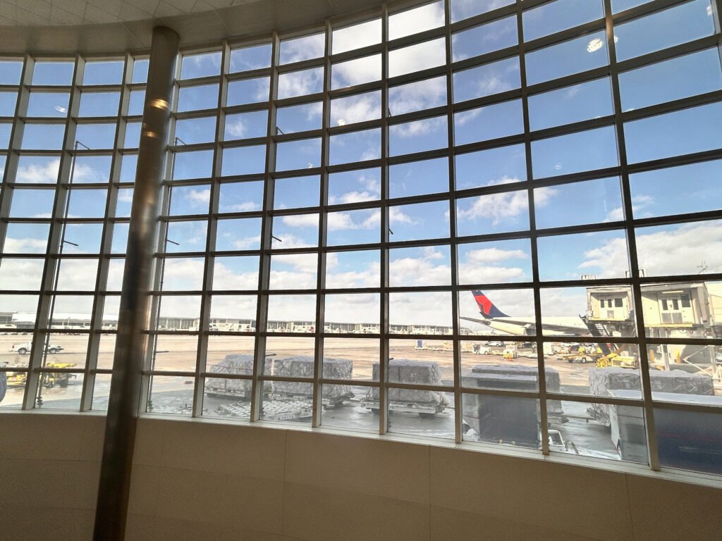 Delta aircraft and baggage containers viewed through large windows at Detroit Airport’s McNamara Terminal.