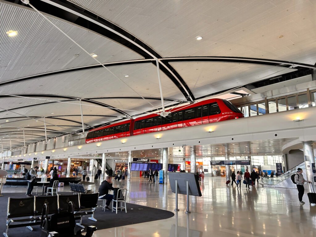 Red ExpressTram travels above passengers inside Detroit Airport’s McNamara Terminal.