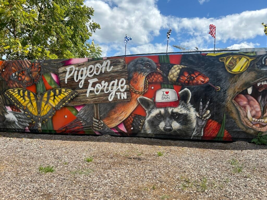 Colorful Pigeon Forge mural featuring a raccoon, black bear, birds, butterflies and Smoky Mountain wildlife.