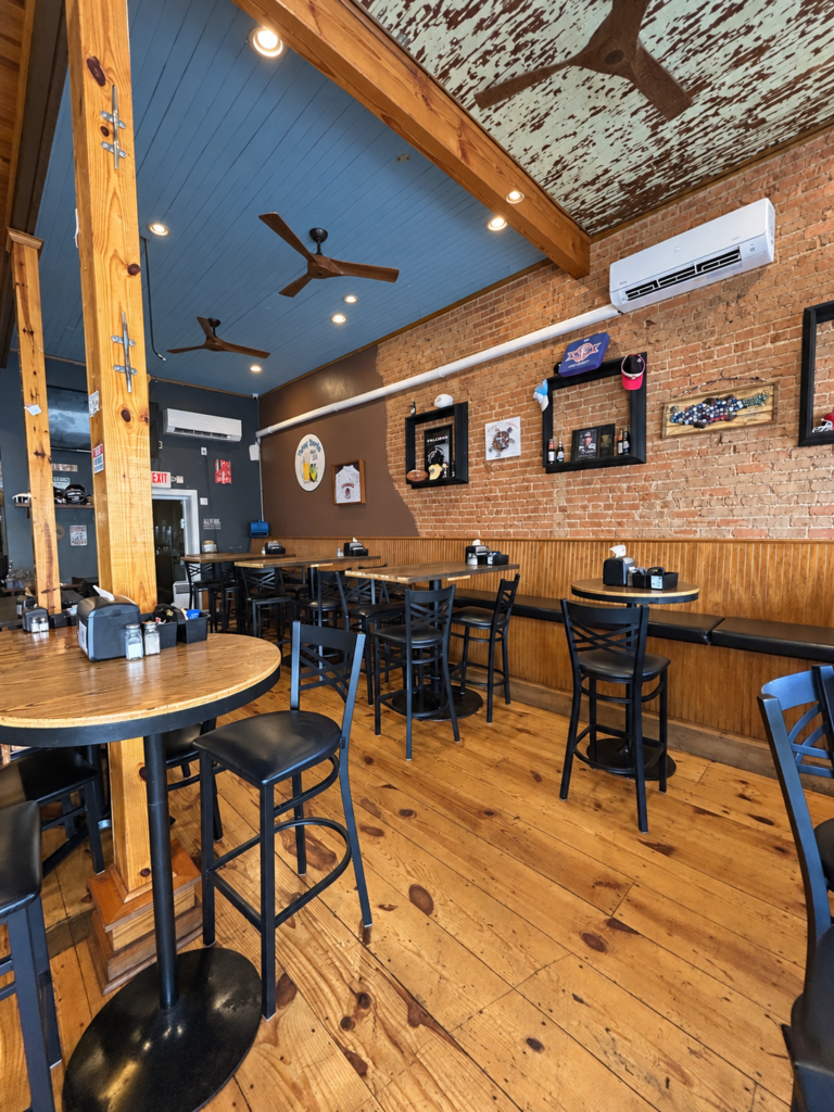 Industrial-style dining room at The Tipsy Turtle with exposed brick walls, wooden tables, and bar seating