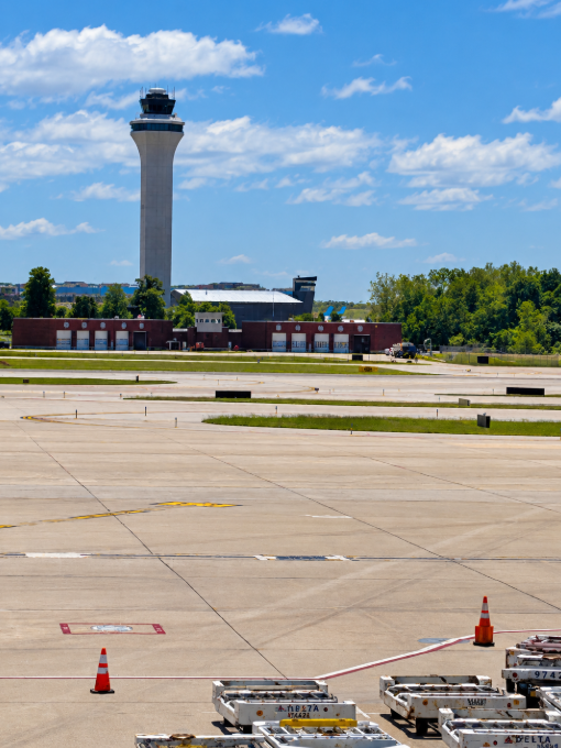Air traffic control tower at CVG, seen across the airport apron and baggage-handling equipment.