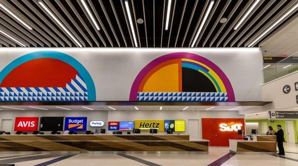 Rental car counters at CVG Airport beneath a large colorful geometric mural.