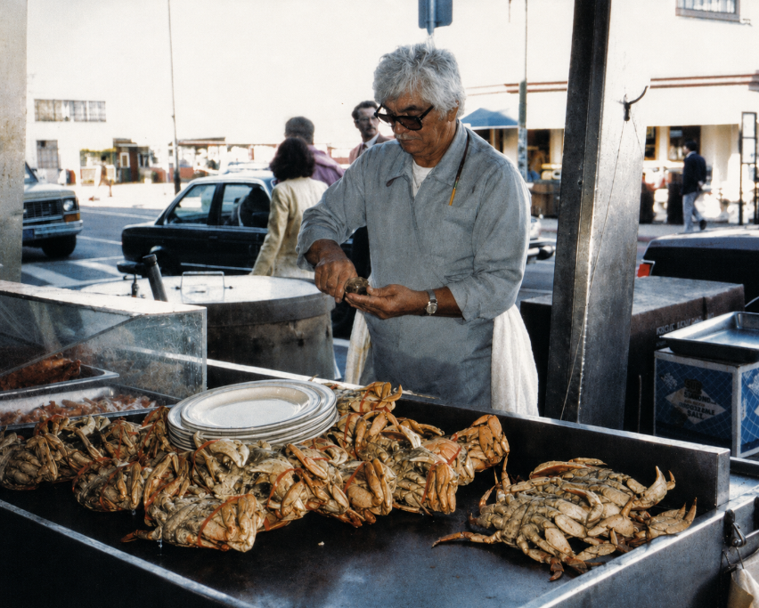 Vintage 1983 photograph of a seafood vendor preparing crabs at Fisherman’s Wharf in San Francisco, with crabs displayed across the counter.
