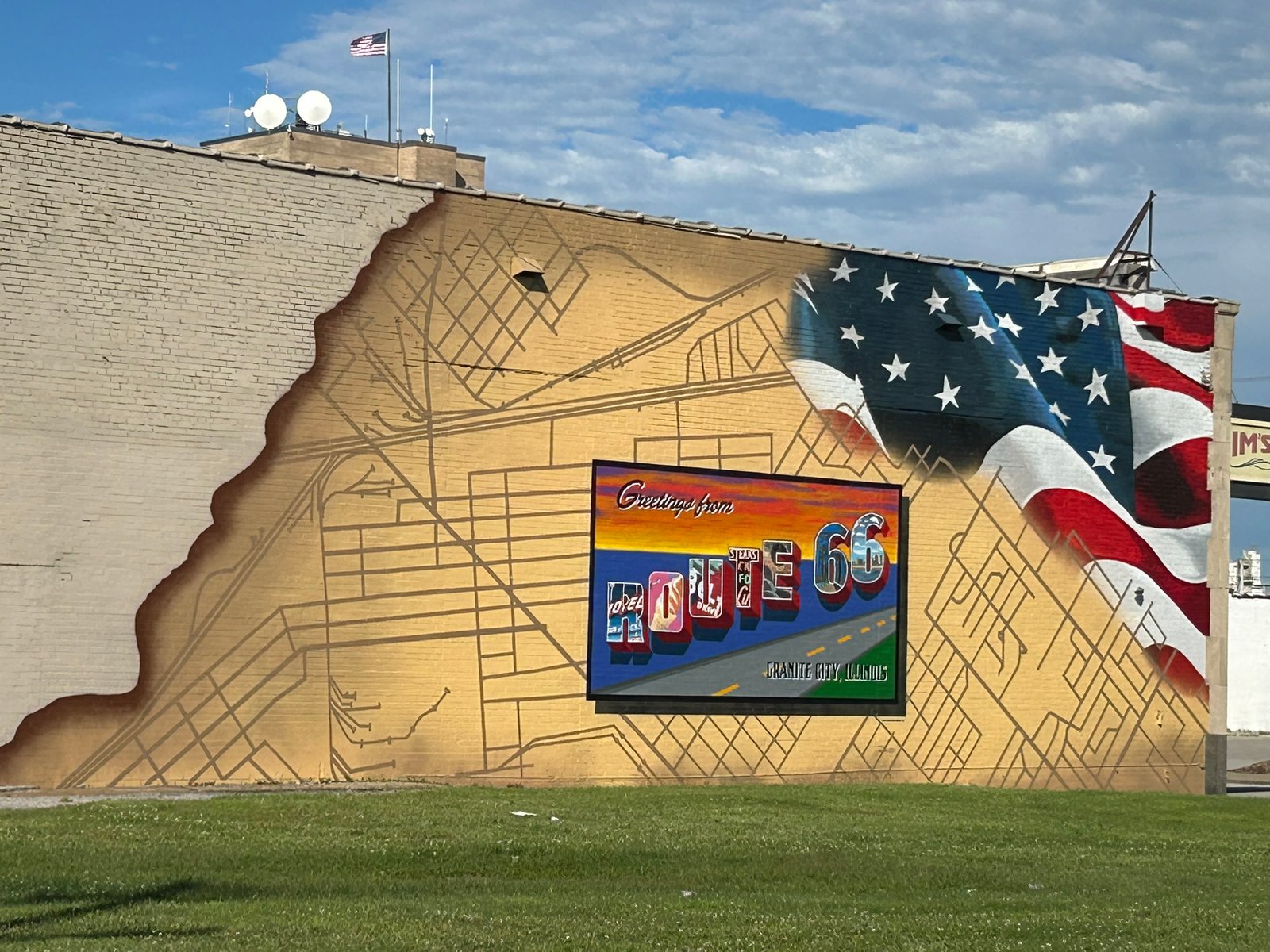 Greetings from Route 66 postcard mural in Granite City, Illinois, featuring a colorful Route 66 sign, American flag, and street-map background