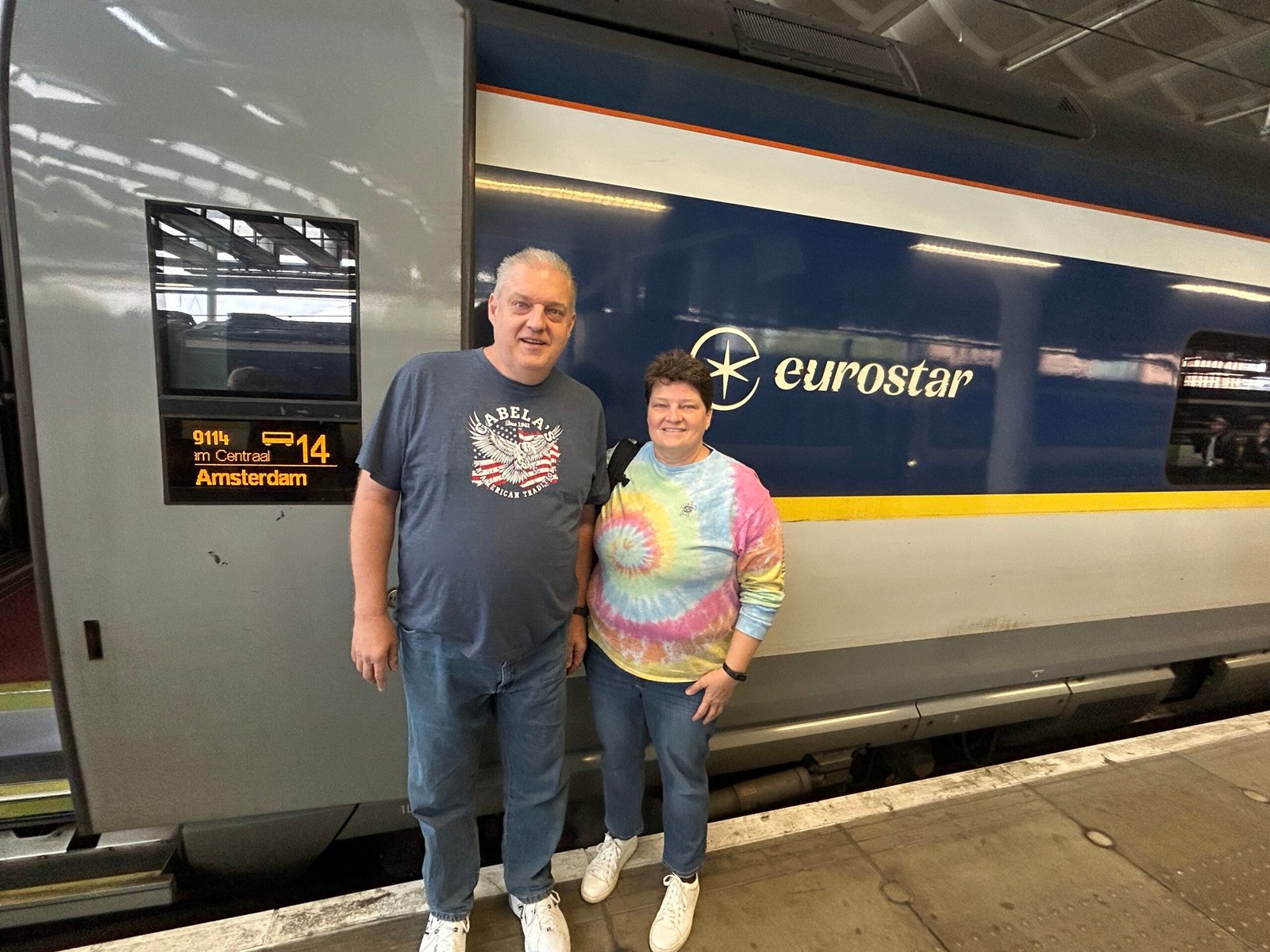 Two travelers standing together beside a Eurostar train at the station