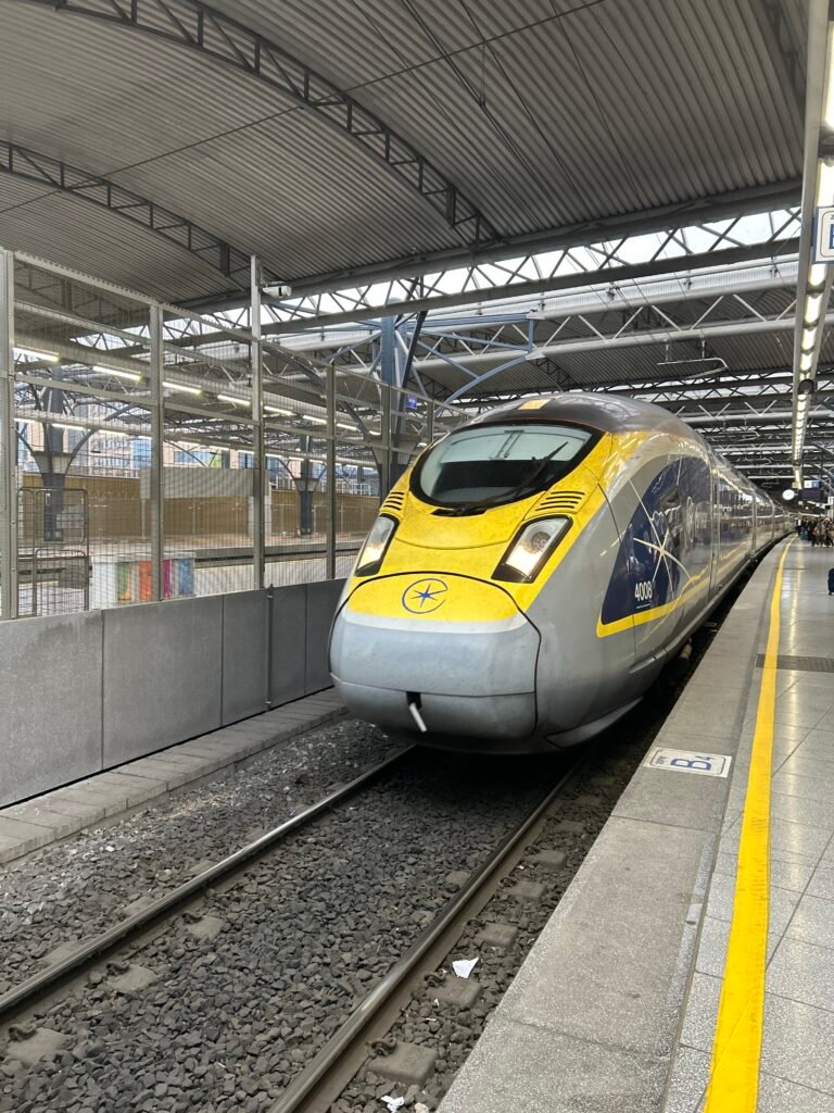 Yellow and blue Eurostar high-speed train waiting at the station platform.
