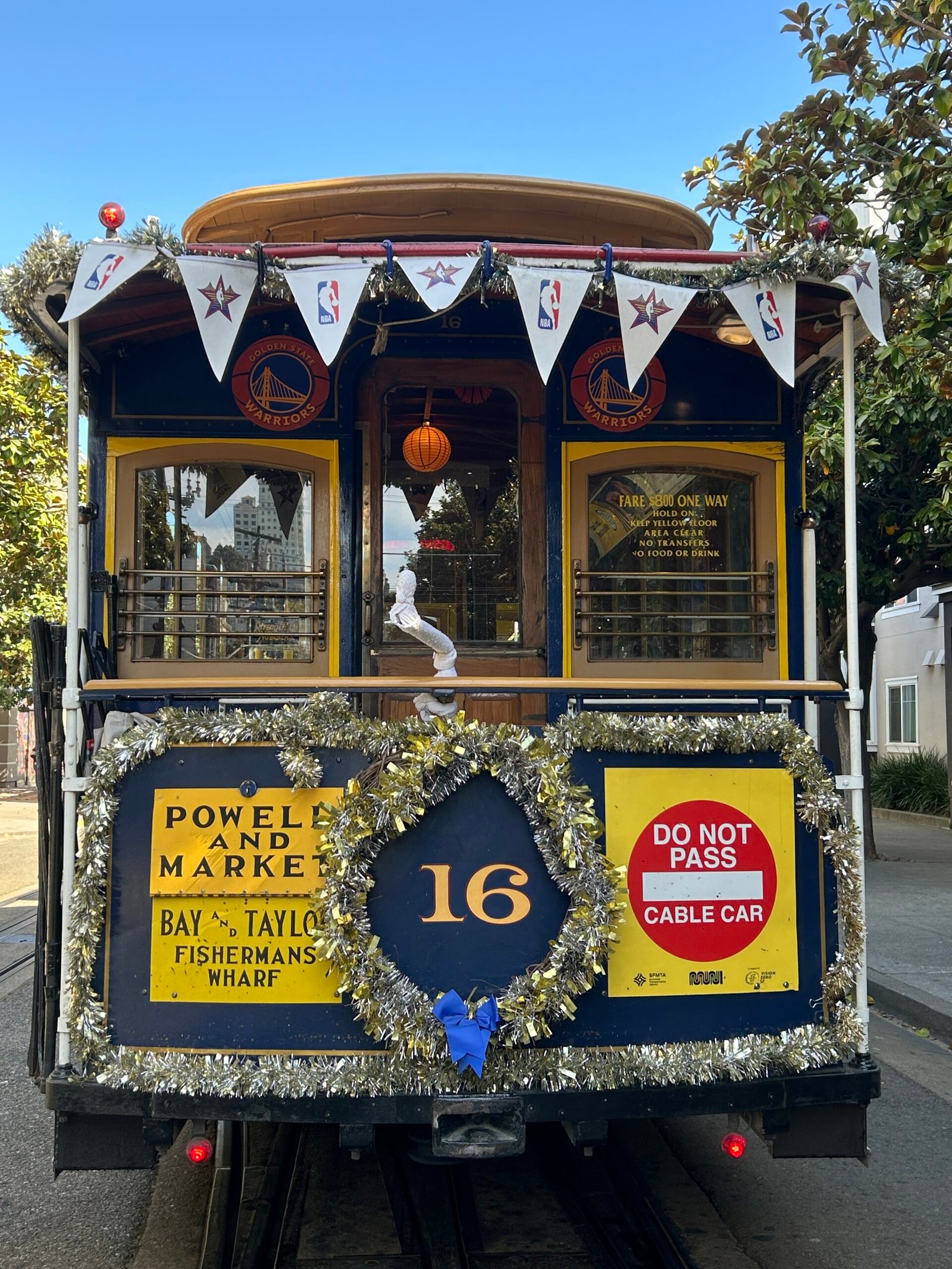 Rear of a San Francisco cable car showing Powell and Market, Bay and Taylor route signs and a Do Not Pass Cable Car warning