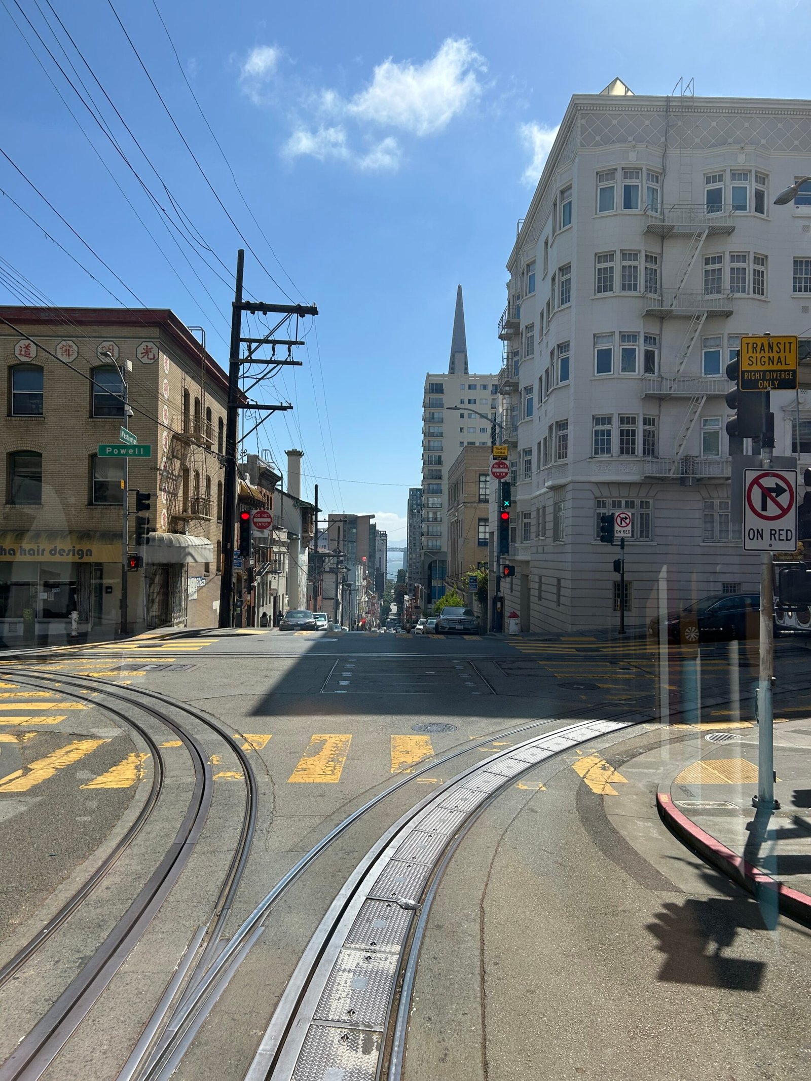 Cable car tracks curving through a San Francisco intersection viewed from aboard a historic cable car